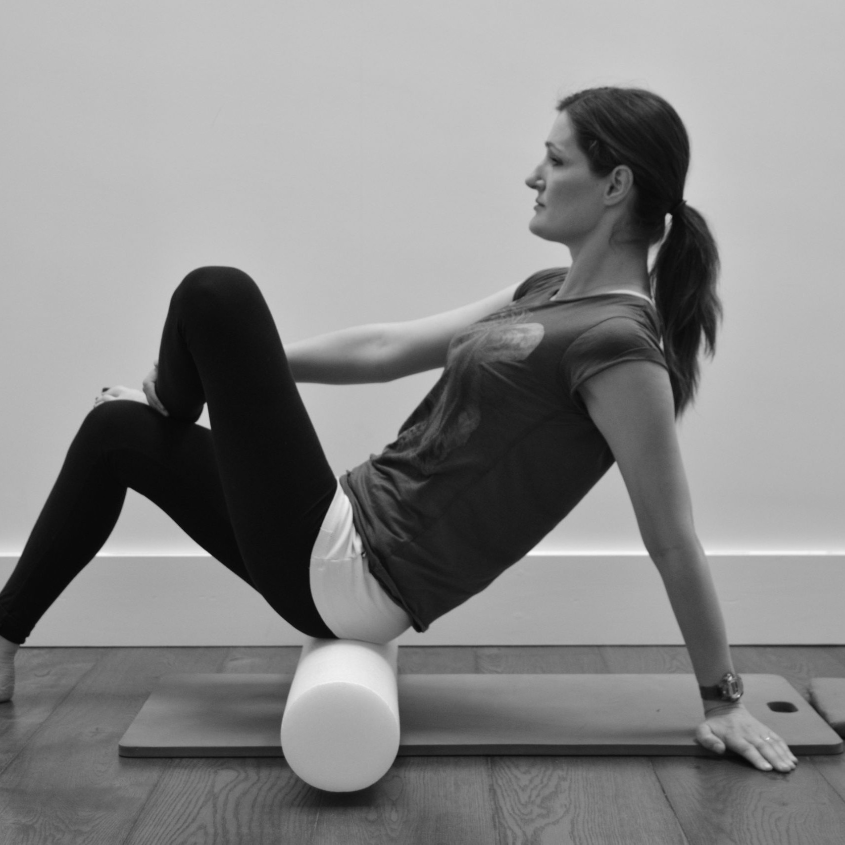 Woman practicing Pilates at home with a foam roller