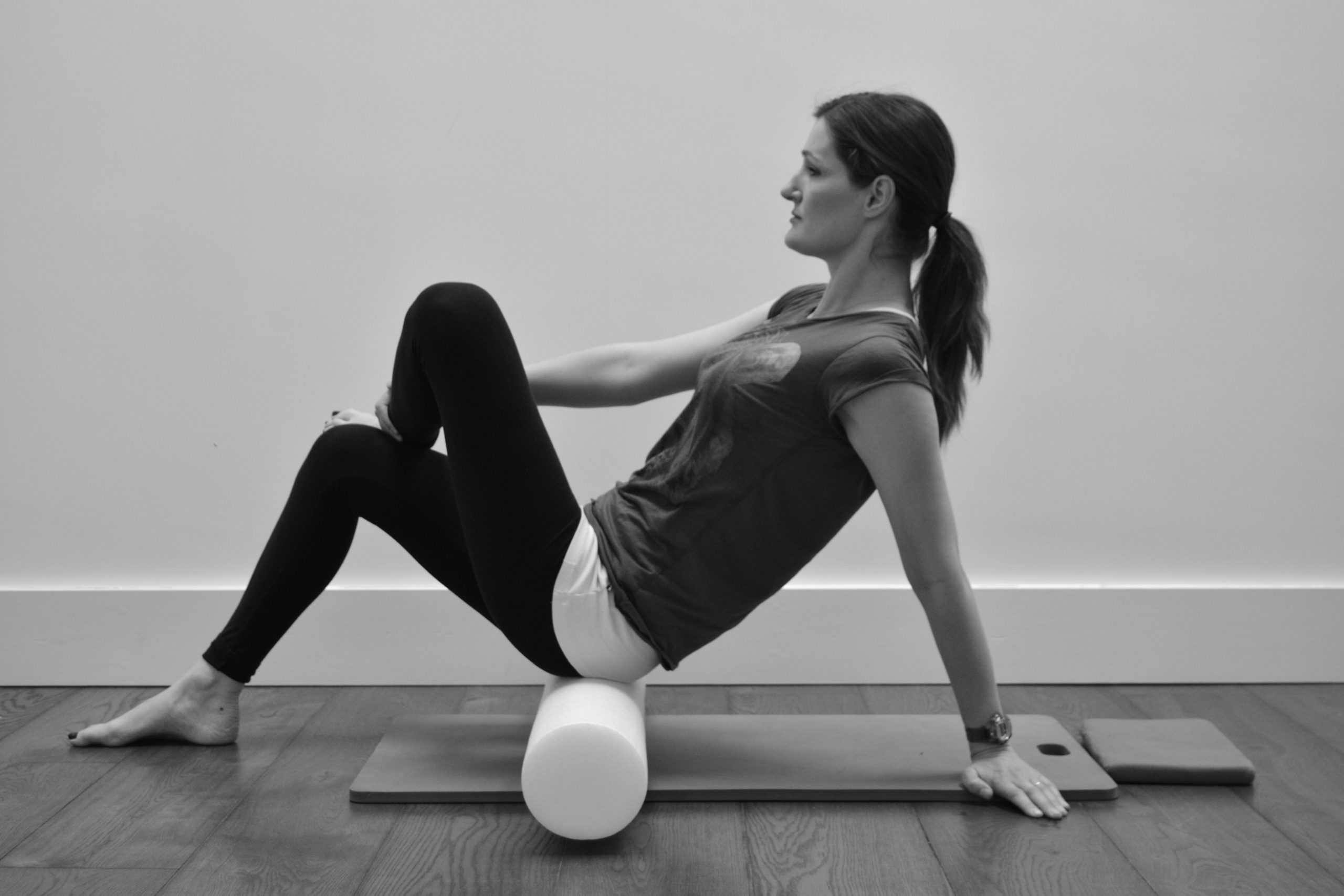 Woman practicing Pilates at home with a foam roller