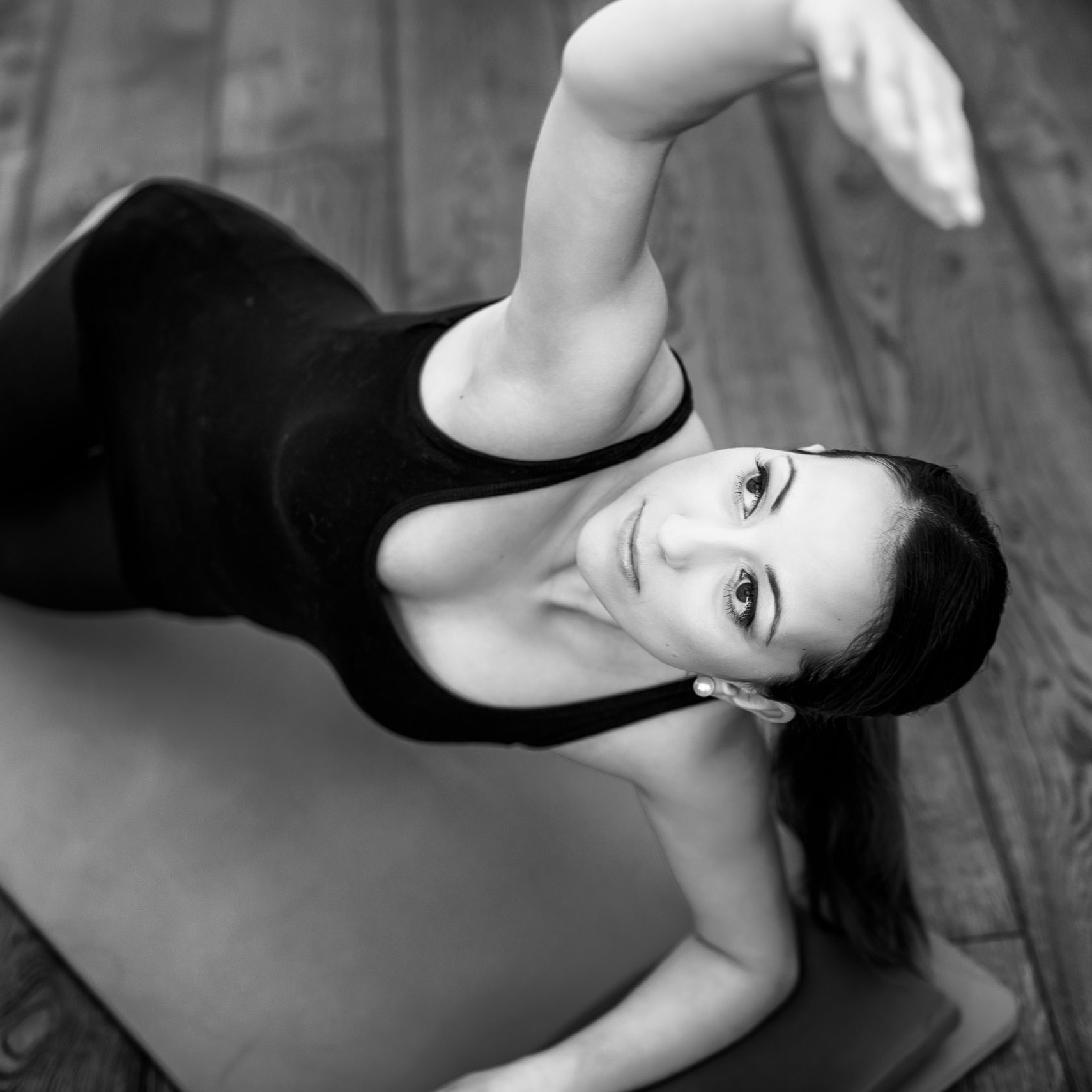 black and white. A woman a Pilates on a mat stretching over head