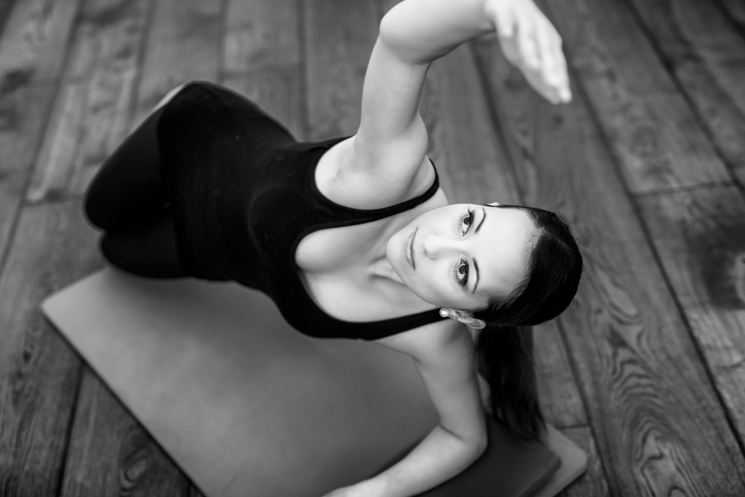 black and white. A woman a Pilates on a mat stretching over head